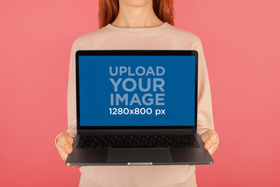 Mockup of a Girl Holding a MacBook In Front of a Solid Color Wall a20565
