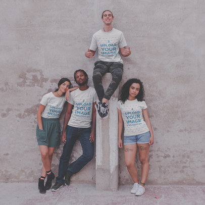 Interracial Group of Four Teens Wearing T-Shirts Mockup Against a Concrete Wall