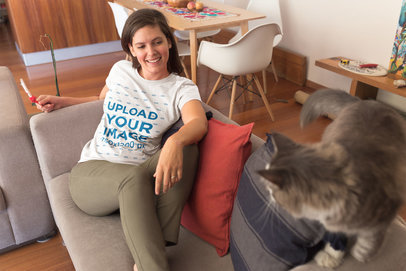 Woman Wearing a T-Shirt Mockup on a Couch with an Angry Cat