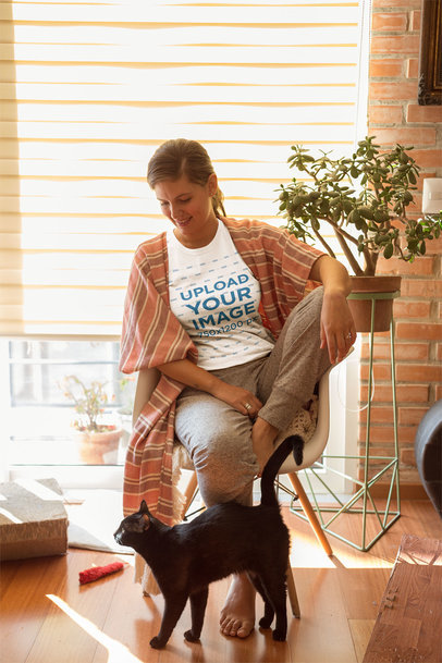 Woman Weaockring Pants and a T-Shirt Mup Sitting Near her Cat
