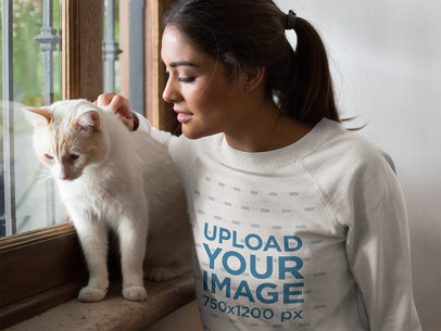 Closeup of a Beautiful Woman Wearing a Crewneck Sweatshirt Mockup Petting a White Cat Near a Window