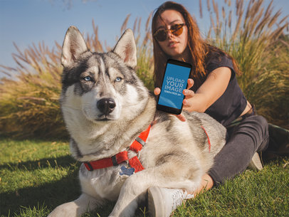 Pretty Woman Showing an App on her iPhone Mockup Above her Dog a19636