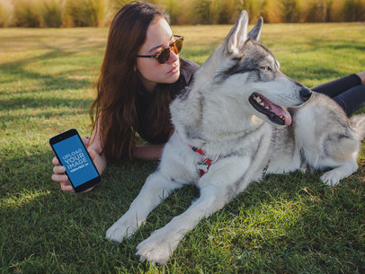 Girl Holding an iPhone 8 Mockup Lying with her Dog at the Park a19645