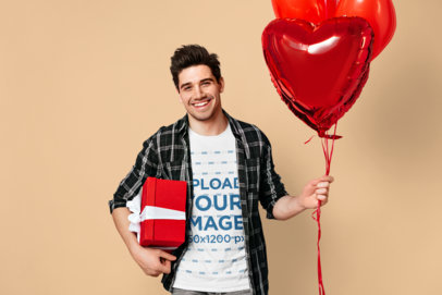 Round-Neck Tee Mockup of a Smiling Man Holding a Heart-Shaped Balloon and a Gift