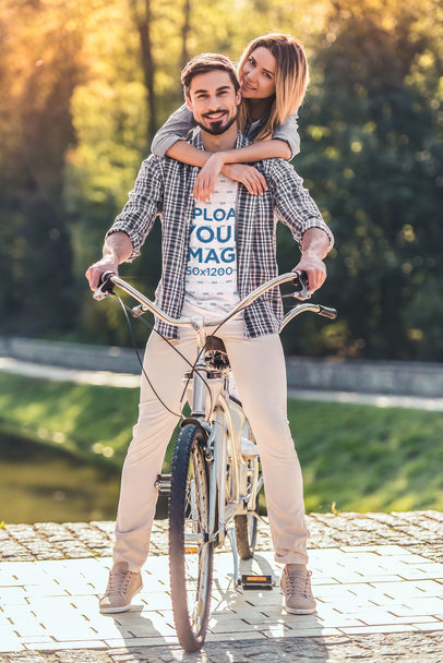 Heathered T-Shirt Mockup Featuring a Couple Riding a Bike in the Park