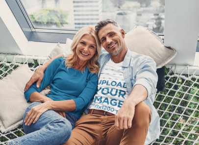 T-Shirt Mockup Featuring a Smiling Couple Hugging by a Window