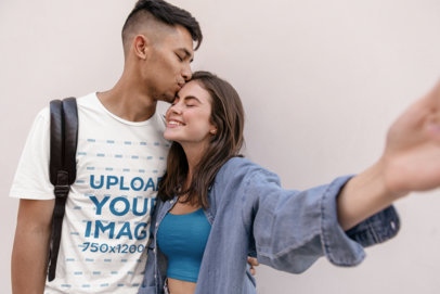 T-Shirt Mockup Featuring a Man Kissing His Girlfriend on Her Forehead While Taking a Selfie