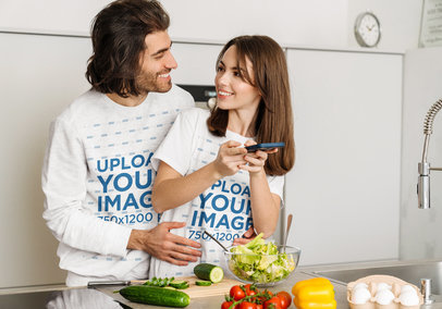 T-Shirt and Heathered Sweatshirt Mockup of a Cute Couple Hugging While Making a Salad