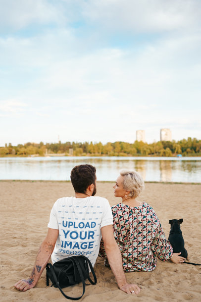 Back-View T-Shirt Mockup Featuring a Tattooed Man Sitting Near a Lake With His Girlfriend