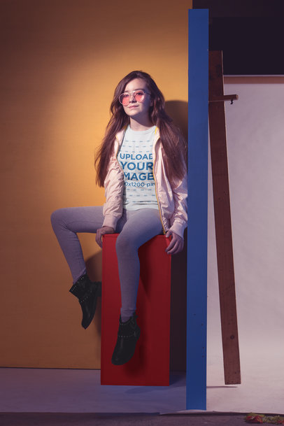 Cool Little Girl Wearing a T-Shirt Mockup Sitting on a Colored Structure
