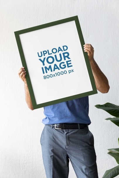 Mockup of a Person Holding an Art Print Mockup Featuring a Plant in the Back