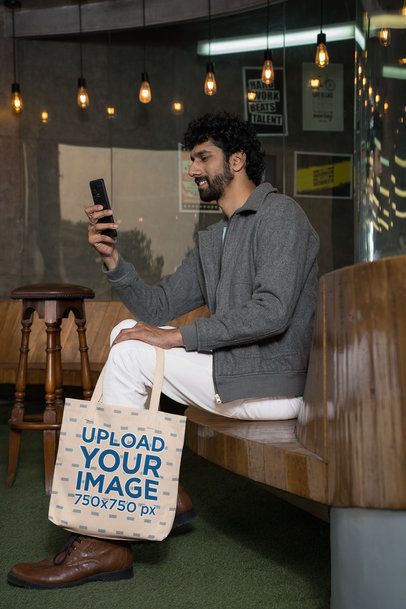 Sublimated Tote Bag Mockup of a Bearded Man Checking His Smartphone
