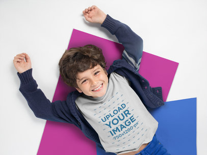 Mockup of a Smiling Kid Wearing a Tshirt Resting Over Pasteboards a19487