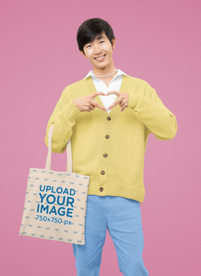 Tote Bag Mockup Featuring a Happy Man Making a Heart Hand Sign