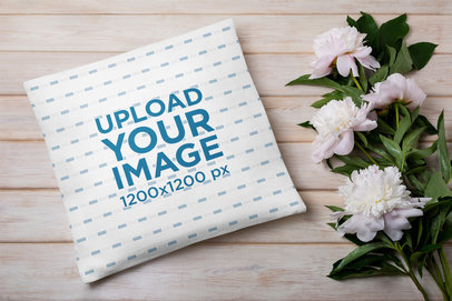 Mockup of a Sublimated Squared Pillow Placed Next to a Mug with Flowers