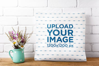 Mockup of a Sublimated Squared Pillow Placed Next to a Mug with Flowers