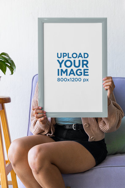 Mockup of a Woman With an Art Print Sitting on a Couch