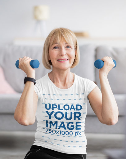 Round-Neck T-Shirt Mockup of an Elderly Woman Holding Vinyl Dumbbells