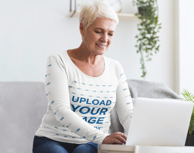 Long-Sleeve Tee Mockup Featuring a Smiling Senior Woman Working on Her Laptop