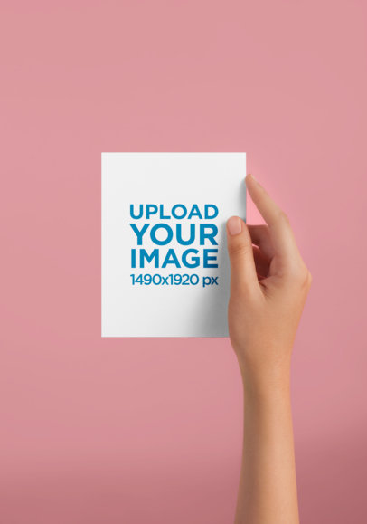 Woman's Hand Holding a Vertical Postcard Mockup Against a Solid Color Surface