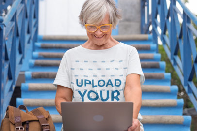 T-Shirt Mockup of an Elderly Woman with Glasses Using a Laptop m18156 r-el2