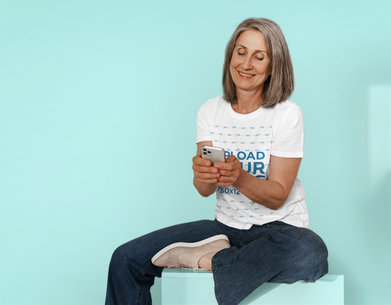T-Shirt Mockup Featuring a Senior Woman Texting Through Her Mobile Phone