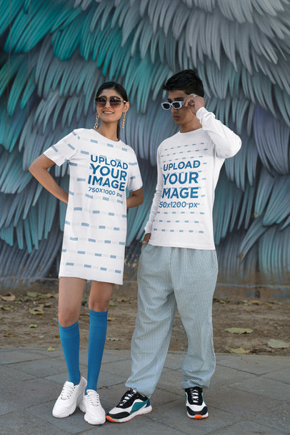 T-Shirt Dress and Long-Sleeve Tee Mockup Featuring a Man and Woman Posing Near a Painted Wall