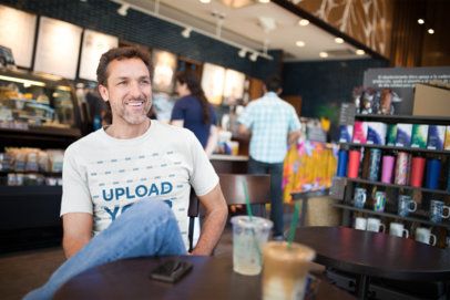 Smiling White Man Wearing a T-Shirt Mockup at a Coffee Shop