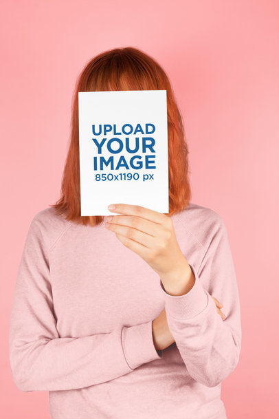 Red-Head Woman Holding a Vertical Postcard Mockup Against her Face