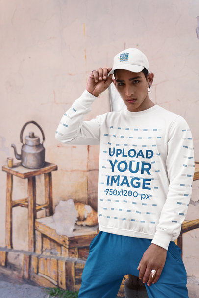 Dad Hat and Sweatshirt Mockup Featuring a Man Posing Against a Painted Wall