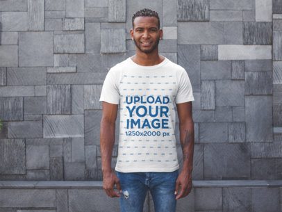 Mockup of a Smiling Man Wearing a Tshirt Standing Against a Modern Stone Wall
