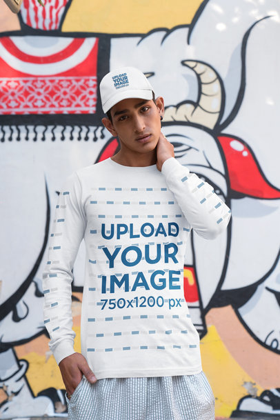 Bella Canvas Long-Sleeve Tee and Dad Hat Mockup of a Serious Man Posing Against a Mural