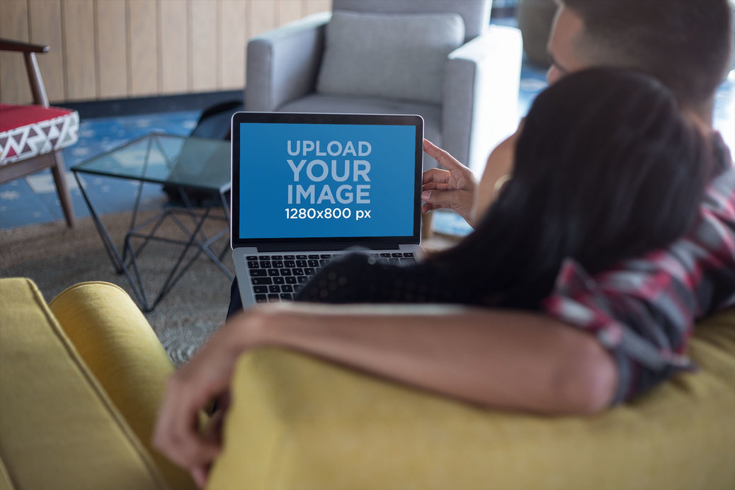 MacBook Mockup Being Used by a Couple Relaxing on a Couch