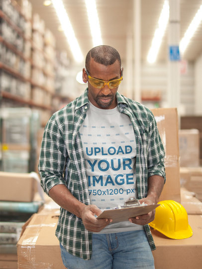 Warehouse Worker Wearing a T-Shirt Mockup While Checking the Inventory