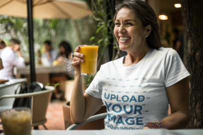 Happy Senior Lady Drinking an Orange Juice Wearing a T-Shirt Mockup a20362