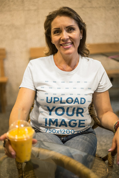 Smiling Senior Woman Wearing a T-Shirt Mockup Having a Smoothie at the Coffee Shop a20367