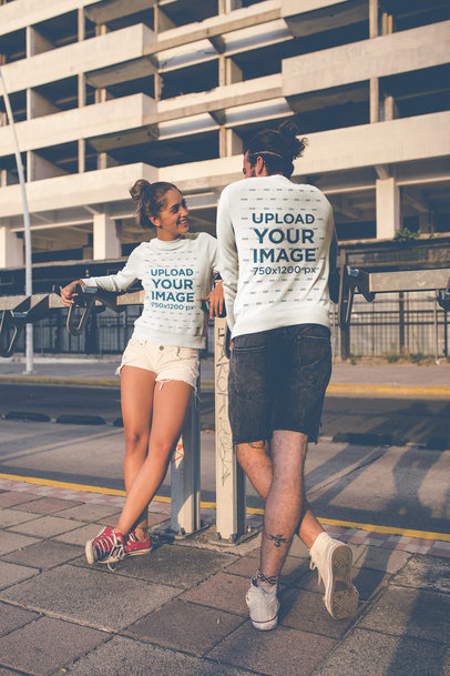Portrait of a Couple Wearing Crewneck Sweaters Mockup Outside a Big Building