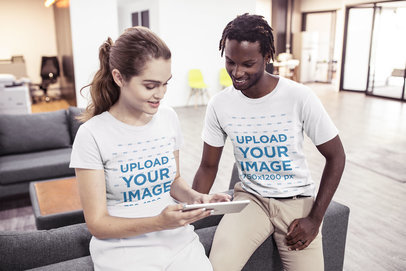 Interracial Pair of Coworkers Wearing T-Shirts Mockup While Discussing a Task