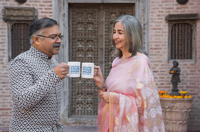Mockup of a Smiling Couple Clinking Their Coffee Mugs