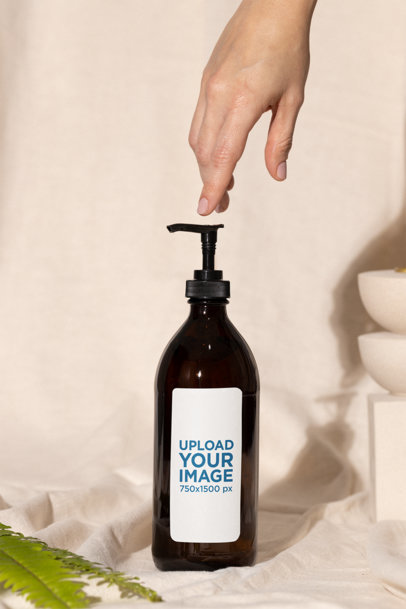 Glass Pump Bottle Mockup Featuring a Person's Hand and an Aesthetic Setting m32214