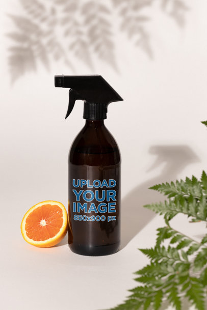 Glass Spray Bottle Mockup Featuring an Orange and Some Plants