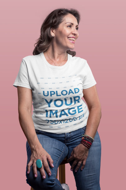 Smiling Senior Woman Wearing a T-Shirt Mockup Sitting on a Stool a20370
