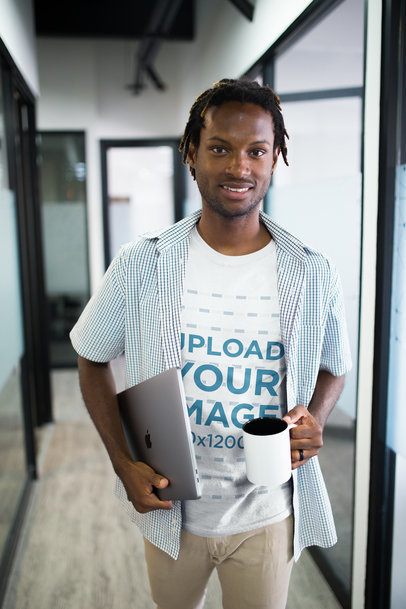 Smiling Man Wearing a Tshirt Mockup Holding a Coffee Cup at an Office