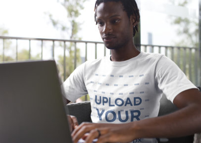 Man Wearing a Tshirt Mockup While Working with his Laptop