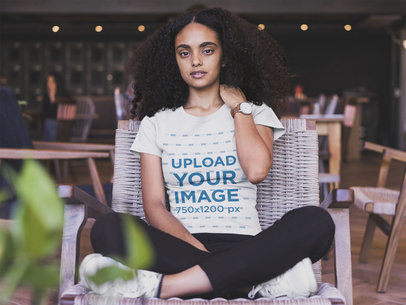 Mockup of a Woman Wearing a T-shirt and Sitting on a Wooden Chair 20417