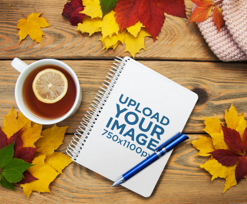 Mockup of a Notebook Placed on a Wooden Table Featuring a Fall Aesthetic