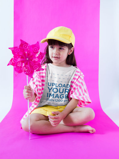 Little Girl Wearing a Round Neck Tee Mockup Holding a Pinwheel