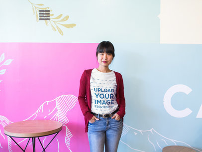 Woman at a Startup Wearing a T-Shirt Mockup Against a Decorated Wall