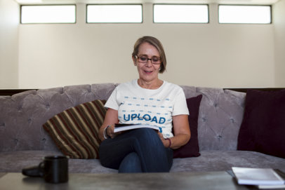 Senior Woman Wearing a Tshirt Mockup Sittng on a Sofa while Reading