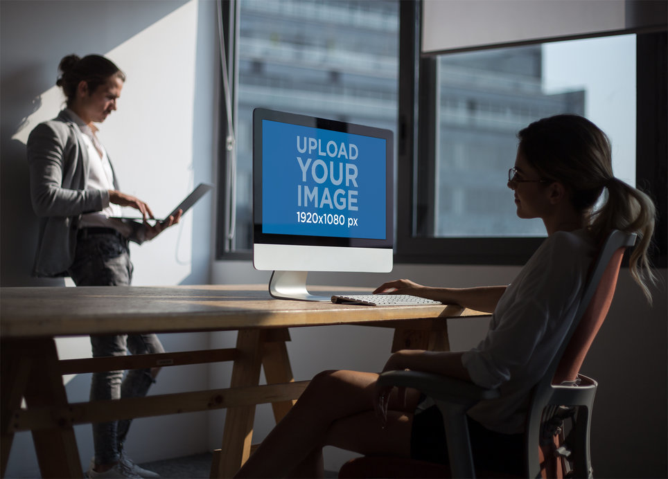 Woman Working with an iMac Mockup Near the Window with her Coworker